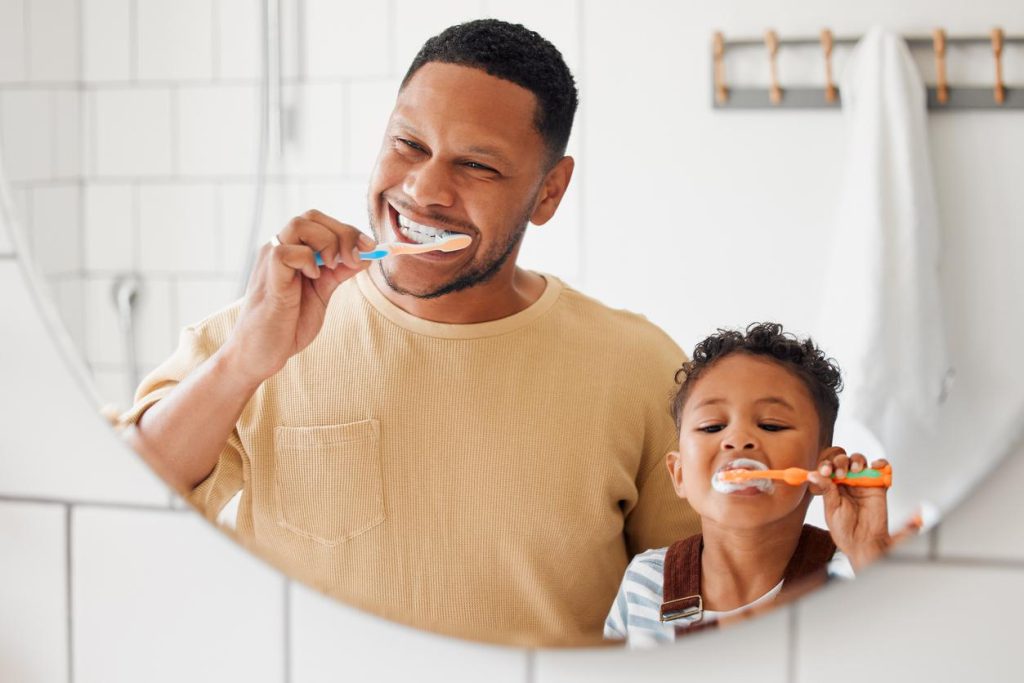 A dad and his daughter brushing their teeth