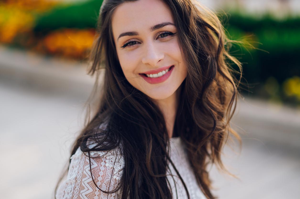 Attractive white woman with long brown hair smiles as she enjoys the nice weather